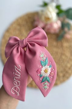 a hand holding a pink bow with flowers on it