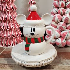 a mickey mouse coffee cup sitting on top of a table next to candy canes