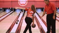 a man and woman standing next to each other at a bowling alley with pins in the lanes