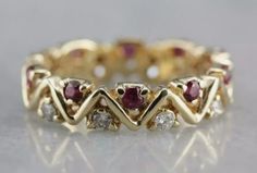 a yellow gold ring with red and white stones on it's sides, sitting on a table