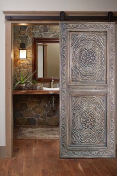 an open door leading to a bathroom with stone walls and wood floors, along with a sink