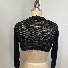 a mannequin wearing a black knitted sweater on top of a dress form