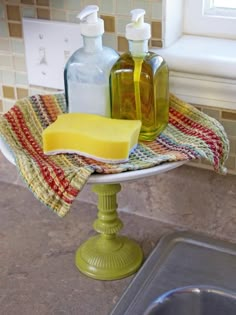 soap and lotion bottles are sitting on a dish towel in a kitchen sink next to a window