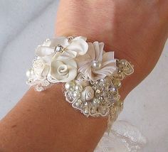 a close up of a person's arm wearing a bracelet with flowers and pearls