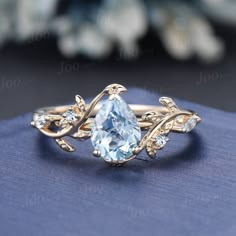 a ring with an aqua blue stone surrounded by leaves