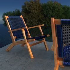 two wooden chairs sitting next to each other on a concrete surface near the water and trees