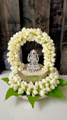 a white flower wreath with an elephant figurine in the middle