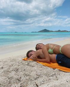 two women laying on a towel at the beach