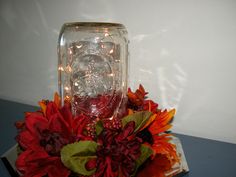 a glass vase with flowers and lights in it