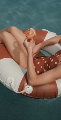 a woman laying on top of an inflatable floating pool floater holding a drink