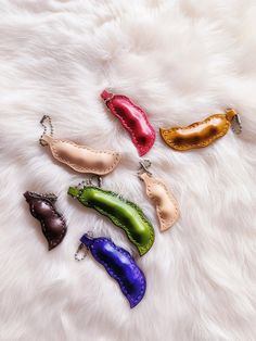 four different colored peppers are laying on a white fur covered surface and one is in the shape of a bell