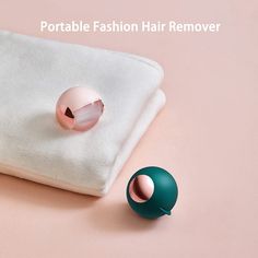 a pair of pink and green earrings sitting on top of a white pillow next to a ball