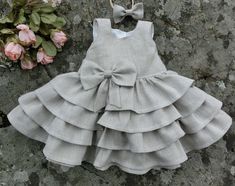 Adorable baby flower girl dress in natural linen. Perfect as an wedding outfit, christening gown, baptism dress, or as any other special occasion dress. This handmade boho linen baptism dress has a poofy ruffle skirt, sash tails sewn into the side seams, by tying them to a big bow in the back, you can adjust the size. The waist is decoarated with a natural linen bow, carefully handcrafted to give this bohemian baby flower girl dress a rustic charm. A back button closure gives the dress a vintage Spring First Communion Dress With Bow, Summer Baptism Dress With Bow, Summer Baptism Dress In Cream For Dress-up Occasions, Summer Cream Baptism Dress For Dress-up Occasions, Fitted Baptism Dress For Summer, Fitted Baptism Dress For Summer Garden Party, Cute Wedding Dress With Bow, Elegant Cotton Baptism Dress, Elegant Summer Baptism Dress With Ruffles