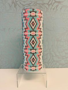 a vase is sitting on a clear stand in front of a blue wall with an intricate pattern