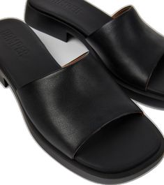 Modern Mules With Rubber Sole, Modern Everyday Mules With Rubber Sole, Modern Mules With Rubber Sole For Everyday, Modern Slip-on Slides, Modern Slip-on Slides With Textured Sole, Modern Slides With Textured Sole, Modern Black Slide Mules, Sleek Leather Slip-on Slides, Modern Slide Mules With Cushioned Footbed