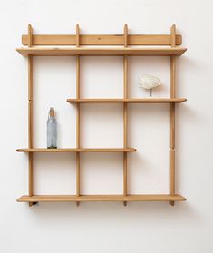 a wooden shelf with two bottles on it and a vase sitting on top of the shelf