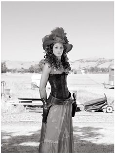 black and white photograph of a woman wearing a dress and hat with her hands on her hips