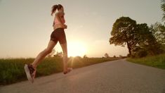 a woman is running down the road in front of the sun with her shoes on