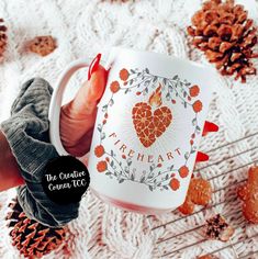 a woman holding a coffee mug with the words true heart on it and pine cones