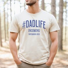 a man standing in the woods wearing a t - shirt that says dadlife incoming november 2020