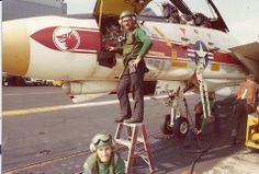 two men standing on ladders in front of an airplane