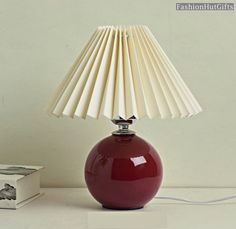 a red lamp sitting on top of a table next to a box and a book