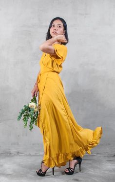 a woman in a yellow dress is posing with her hand on her hip and looking up