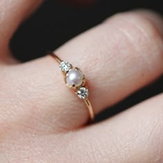 a woman's hand with a pearl and diamond ring on top of her finger