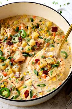 a white bowl filled with chicken and corn chowee next to a spoon on a table