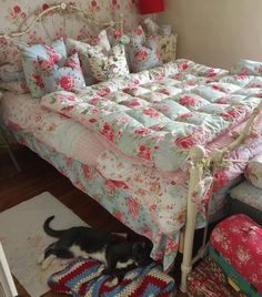 a dog laying on the floor next to a bed with floral bedspread and pillows