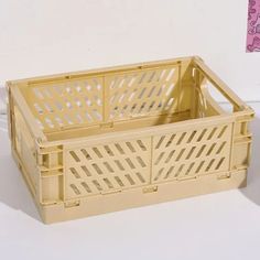 a yellow plastic crate sitting on top of a white table next to a pink wall