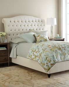 a bed with a white headboard and blue comforter in a light colored bedroom