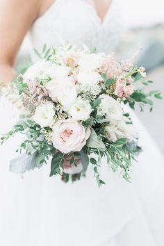 a bridal holding a bouquet of white and pink flowers