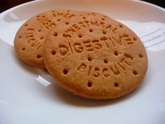 two cookies on a white plate with writing on the top one is round and has holes in it