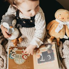 a small child is reading a book with stuffed animals