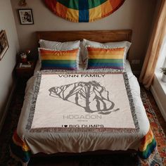 a bed with a rainbow colored comforter and matching pillow cases is in front of a window