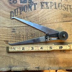 a pair of scissors sitting on top of a wooden table next to a measuring tape