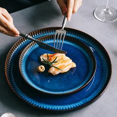 a person is holding a fork and knife over a blue plate with food on it