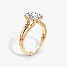 a yellow gold engagement ring with an oval cut diamond in the center and side stones