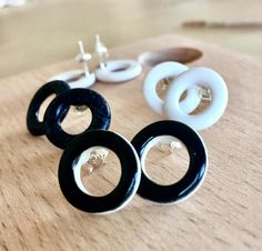 three pairs of black and white earrings sitting on top of a wooden table next to buttons