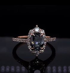 an oval shaped black diamond surrounded by white and brown diamonds in a halo setting on a black background