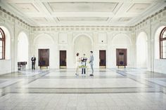 two people standing in an empty building with doors and windows on either side of them