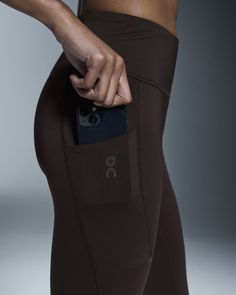 a woman is holding her cell phone in her pocket while wearing leggings and sports bra