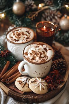 two mugs filled with hot chocolate and cinnamon on top of a wooden platter