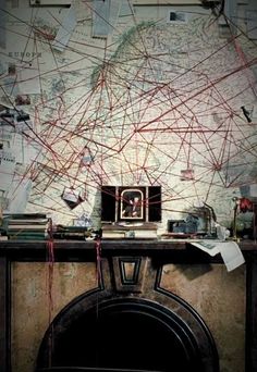 a room with a fire place and a map on the wall behind it, all covered in red string