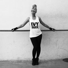 black and white photograph of a woman in tights leaning on a rail with her arms outstretched