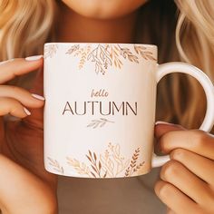 a woman holding a coffee mug with the words hello autumn on it