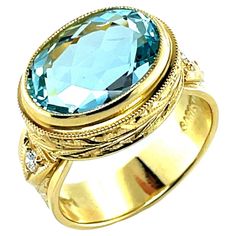 This beautiful handmade ring features a sparkling 6.16 carat oval aquamarine set in 18k yellow gold with diamonds! The center stone has classic aquamarine color - bright crystalline blue so easily recognizable as March's birthstone. The oval is set "east-west" in a handmade 18k yellow gold bezel that has been beautifully hand engraved all around with an intricate leaf pattern. Single white diamonds in their own handmade settings adorn each side of the 7mm wide, hand engraved band. This ring is a Hand Engraved Rings, Aquamarine Color, Aquamarine Colour, Engraved Ring, Gold Hand, Gold Hands, East West, March Birth Stone, White Diamonds