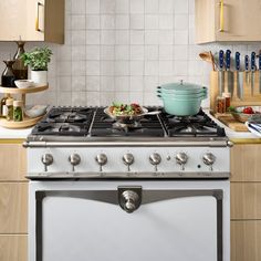 a stove top oven sitting in a kitchen next to a counter with pots and pans on it