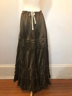 This 1910s-20s petticoat is a light-catching metallic brown/copper/bronze. It has a drawstring waist, and three small metal snaps for the closure. There is one pocket, about 7" down from the waist. The skirt has four tiers of ruffles, including those on the hem.  This skirt shows some wear on the ruffles at the hem, and the drawstring is visible on one part of the waistband. It is otherwise in good vintage condition.  Waist: 24"+ Hip: 60"+ Length: 36" Vintage Brown Tiered Skirt, Brown Vintage Tiered Skirt, Brown Long Skirt, Long Brown Skirt, Brown Copper, Brown Skirt, Alexandria Va, Petticoat, Long Skirt